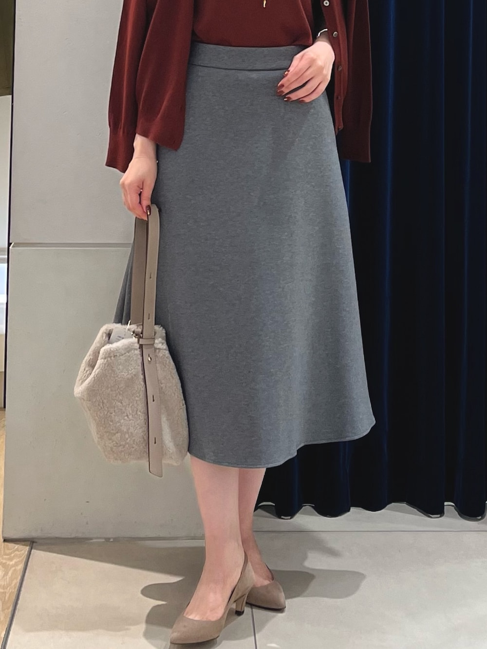 レッド系のニット/セーター、レッド系のカーディガン/ボレロ、グレー系のスカートを着用したレディースの秋コーディネートの4枚目の写真