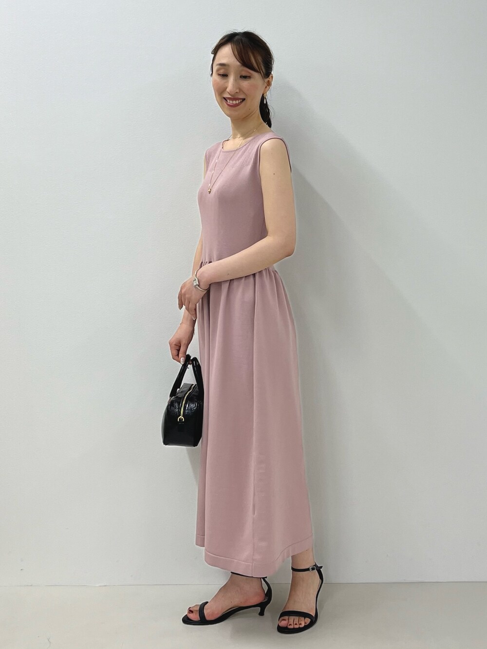 ピンク系のワンピース、ブラック系のサンダル、ゴールド系のピアス(両耳用)を着用したレディースの夏コーディネートの6枚目の写真