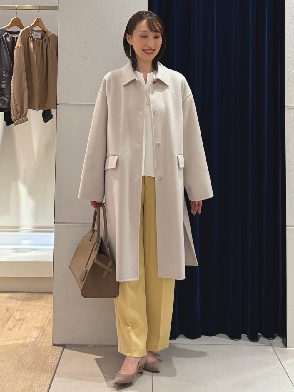 ベージュ系のステンカラーコート、ホワイト系のTシャツ/カットソー、イエロー系のその他パンツを着用したレディースの秋コーディネートの5枚目の写真