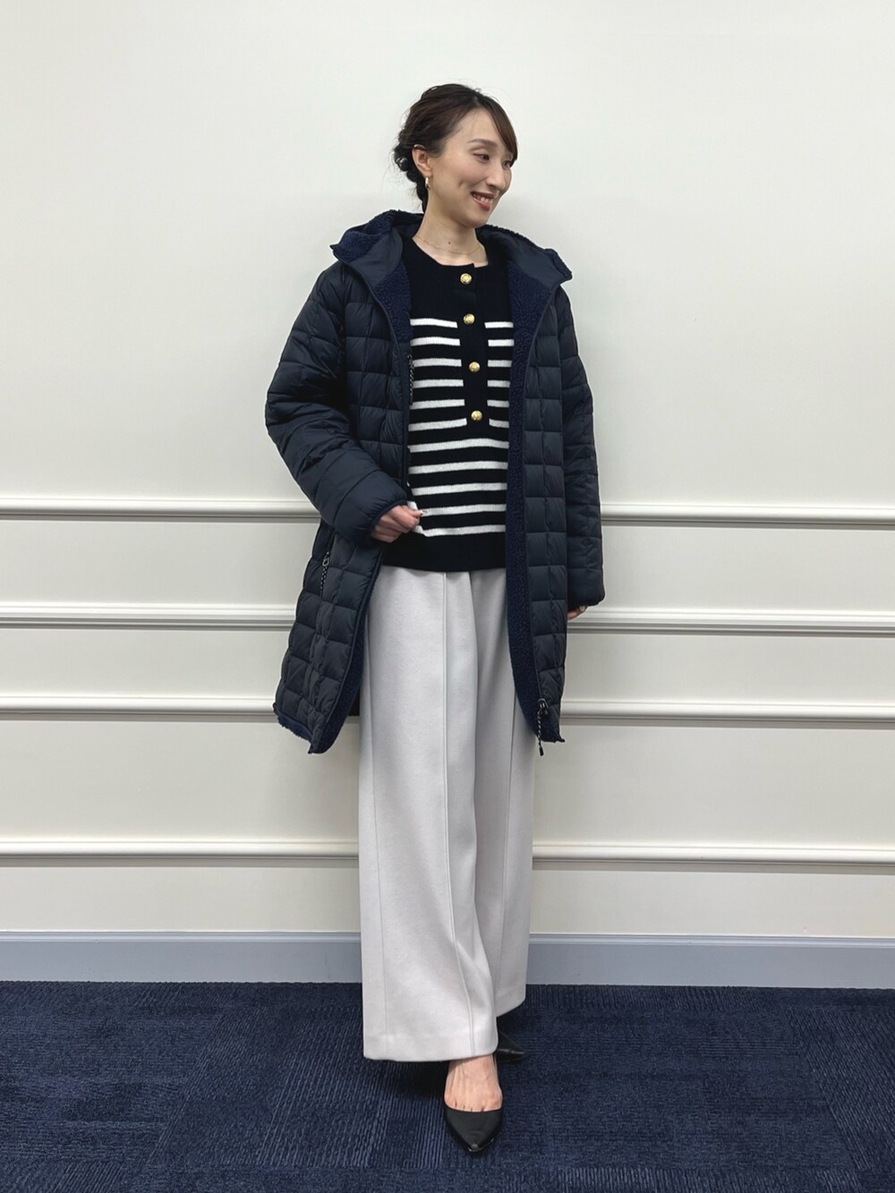 ブルー系のダウンジャケット/コート、ブラック系のニット/セーター、ベージュ系のその他パンツを着用したレディースの秋コーディネートの2枚目の写真