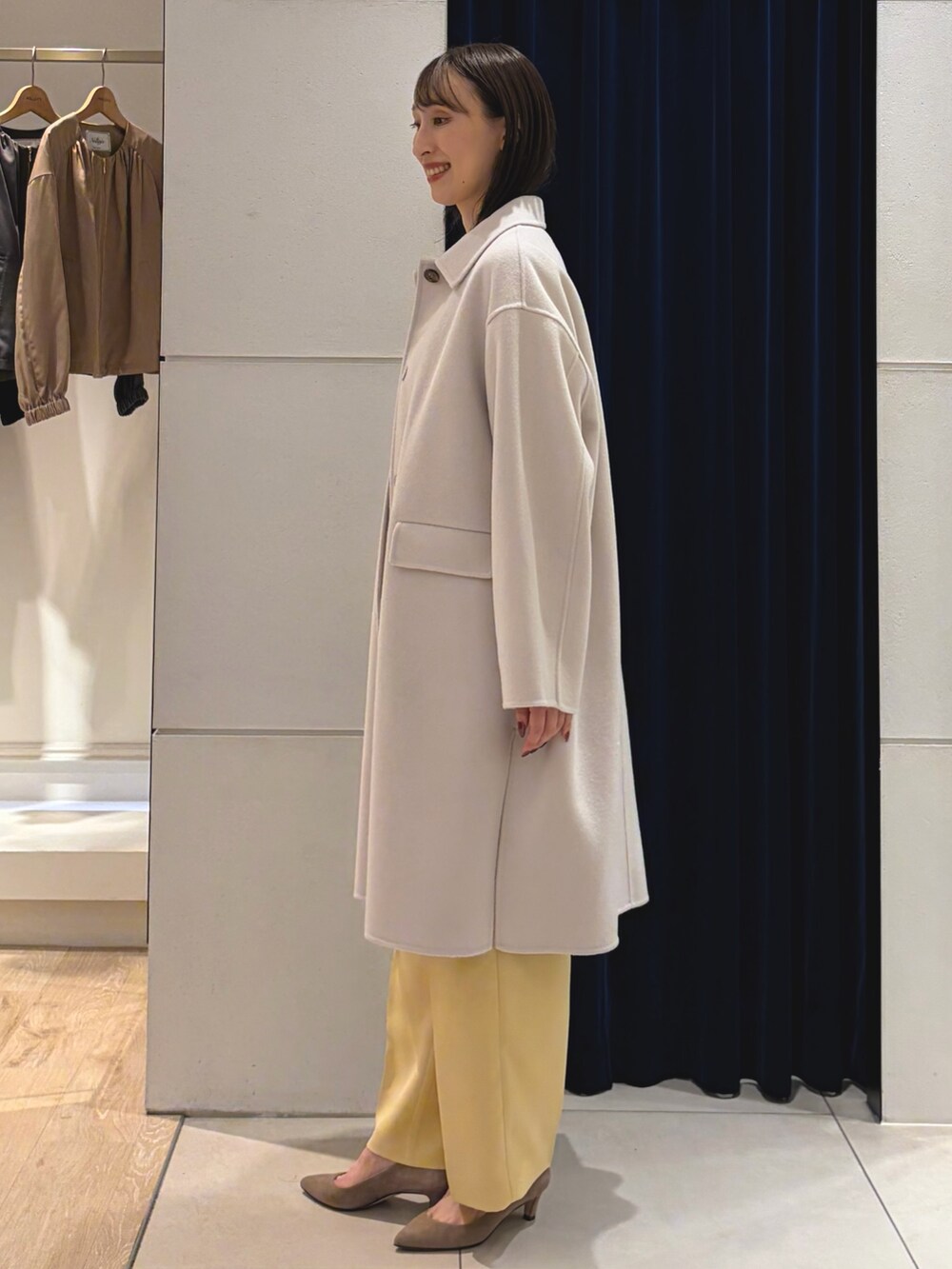 ベージュ系のステンカラーコート、ホワイト系のTシャツ/カットソー、イエロー系のその他パンツを着用したレディースの秋コーディネートの7枚目の写真