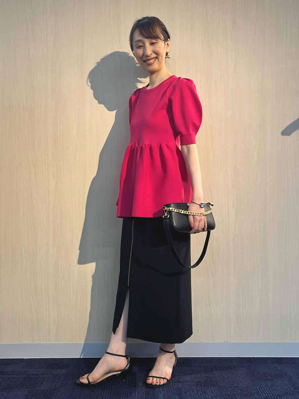 ピンク系のニット/セーター、ブラック系のショルダーバッグ、ブラック系のスカートを着用したレディースの夏コーディネートの3枚目の写真