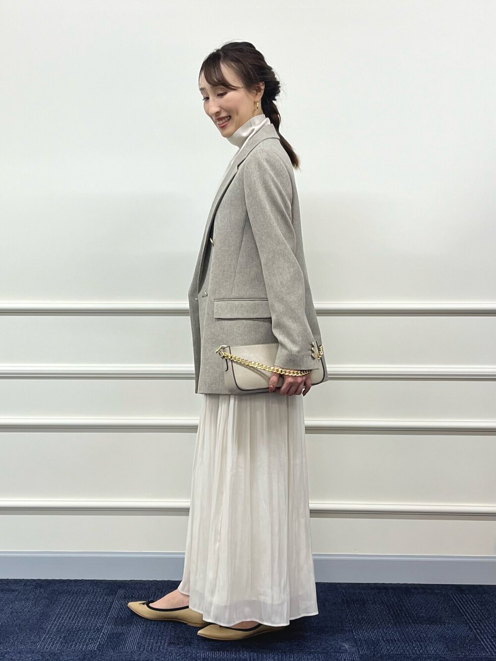 ゴールド系のニット/セーター、ベージュ系のテーラードジャケット、ホワイト系のスカートを着用したレディースの秋コーディネートの4枚目の写真