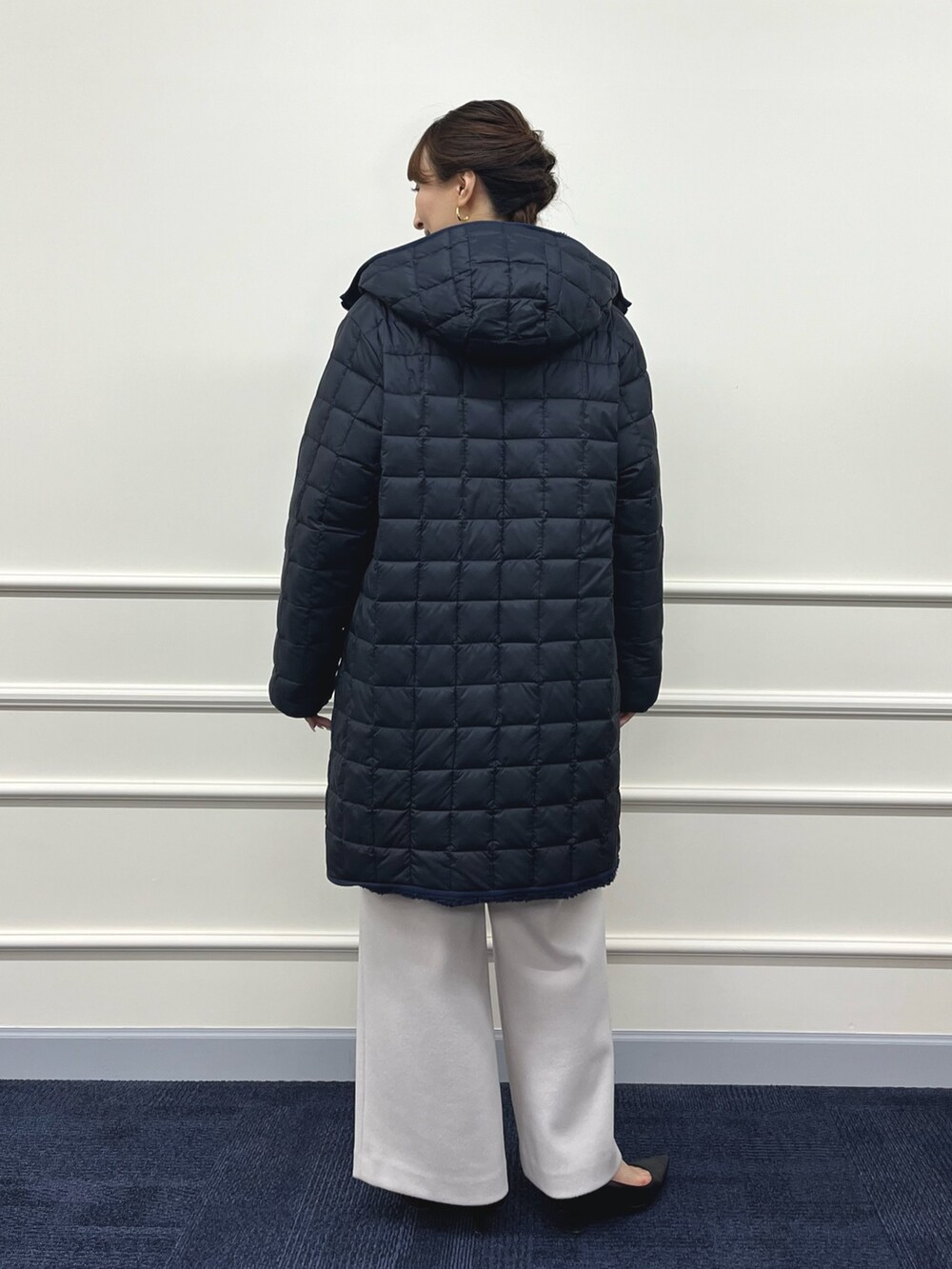 ブルー系のダウンジャケット/コート、ブラック系のニット/セーター、ベージュ系のその他パンツを着用したレディースの秋コーディネートの5枚目の写真