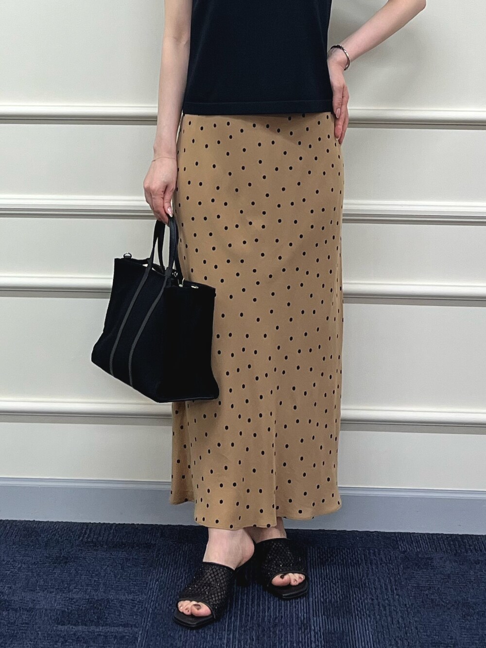 ブラック系のニット/セーター、ブラウン系のスカート、ブラック系のトートバッグを着用したレディースの夏コーディネートの7枚目の写真