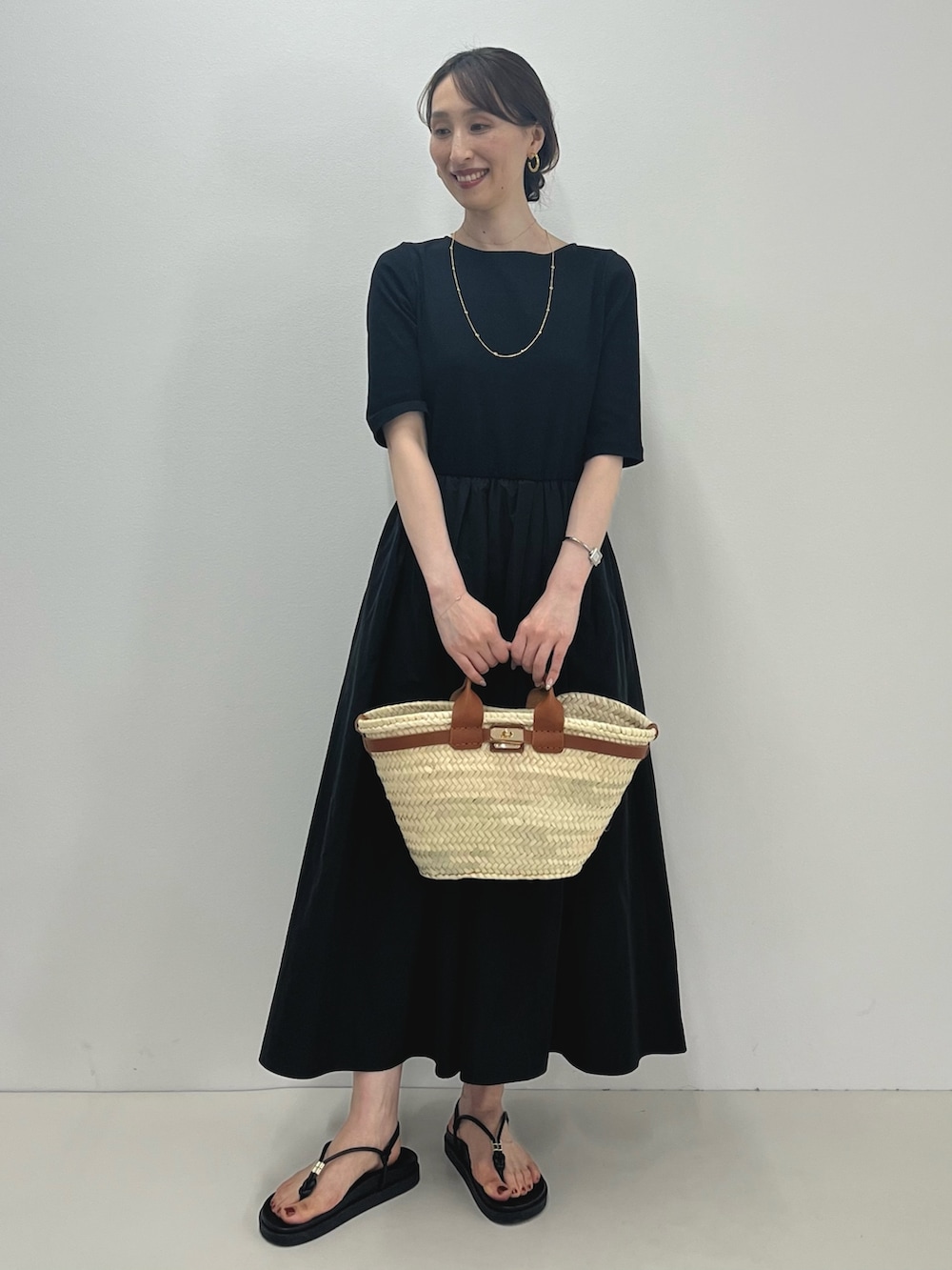ブラック系のワンピース、ブラウン系のかごバッグ、ブラック系のサンダルを着用したレディースの春コーディネートの9枚目の写真