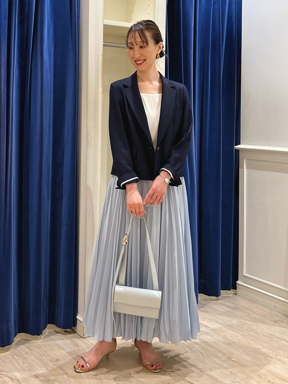 ブルー系のテーラードジャケット、ホワイト系のタンクトップ、ブルー系のスカートを着用したレディースの夏コーディネートの6枚目の写真