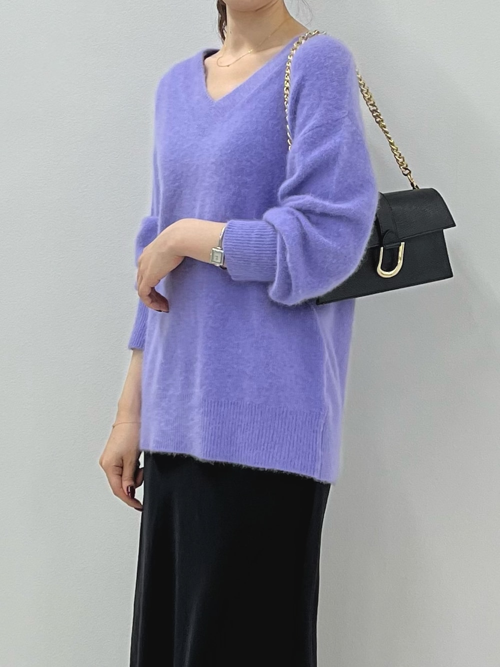 パープル系のニット/セーター、ゴールド系のショルダーバッグ、ブラック系のスカートを着用したレディースの秋コーディネートの4枚目の写真