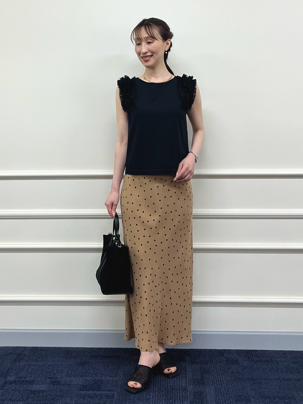 ブラック系のニット/セーター、ブラウン系のスカート、ブラック系のトートバッグを着用したレディースの夏コーディネートの9枚目の写真