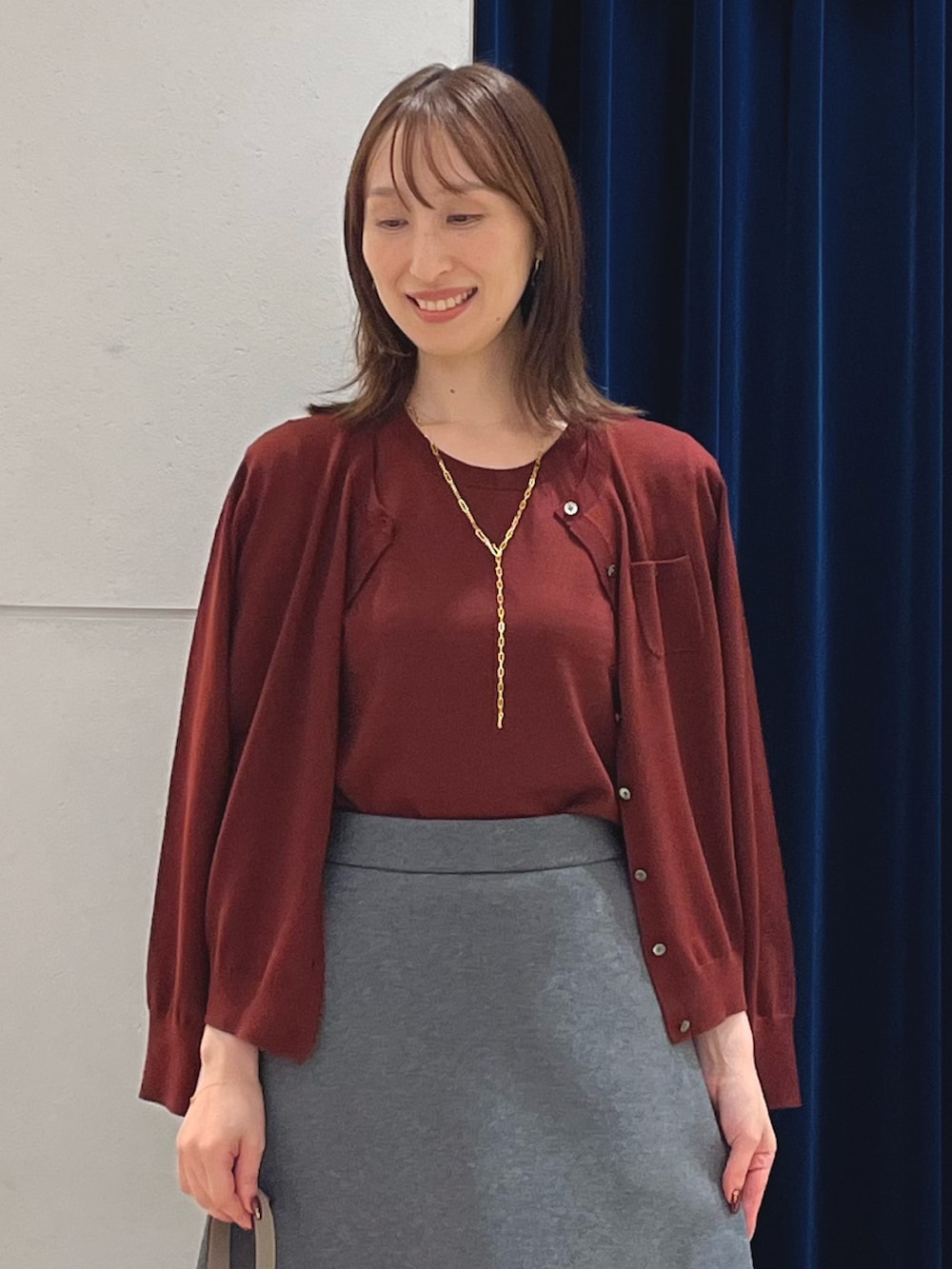 レッド系のニット/セーター、レッド系のカーディガン/ボレロ、グレー系のスカートを着用したレディースの秋コーディネートの3枚目の写真