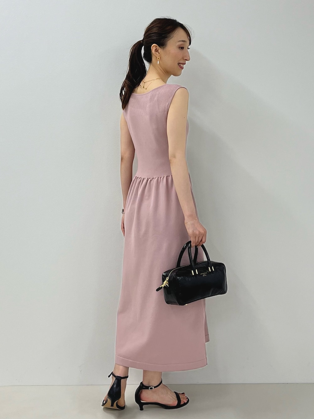 ピンク系のワンピース、ブラック系のサンダル、ゴールド系のピアス(両耳用)を着用したレディースの夏コーディネートの8枚目の写真