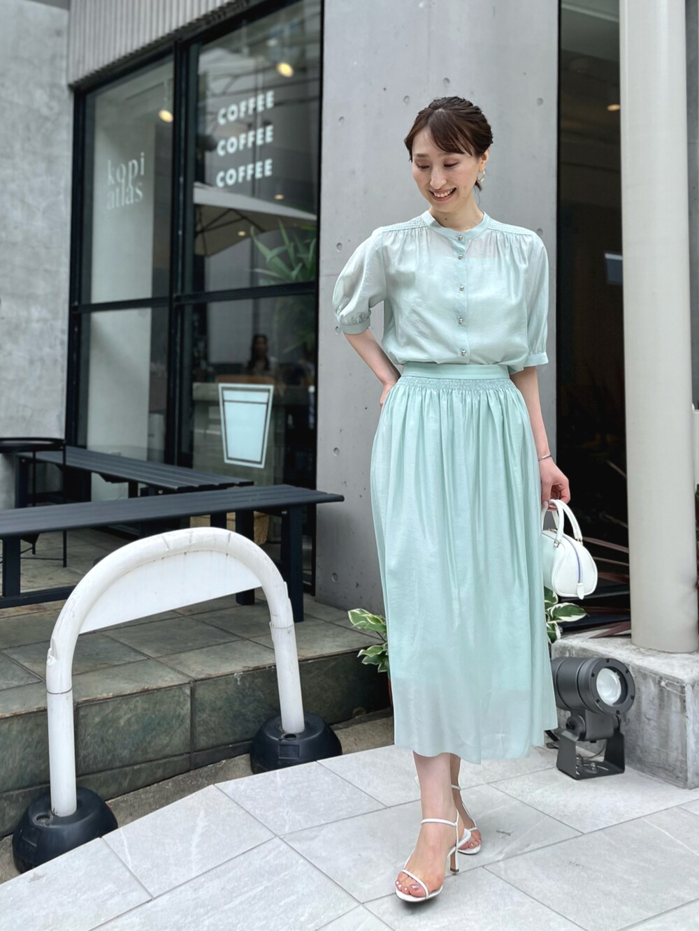 グリーン系のシャツ/ブラウス、グリーン系のスカート、ホワイト系のボストンバッグを着用したレディースの春コーディネートの4枚目の写真
