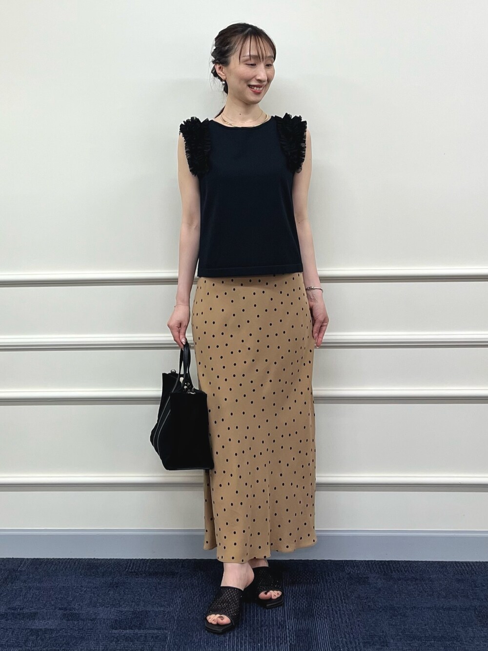 ブラック系のニット/セーター、ブラウン系のスカート、ブラック系のトートバッグを着用したレディースの夏コーディネートの2枚目の写真