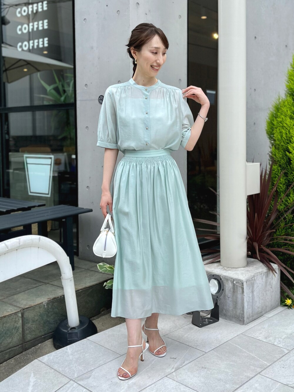 グリーン系のシャツ/ブラウス、グリーン系のスカート、ホワイト系のボストンバッグを着用したレディースの春コーディネートの2枚目の写真
