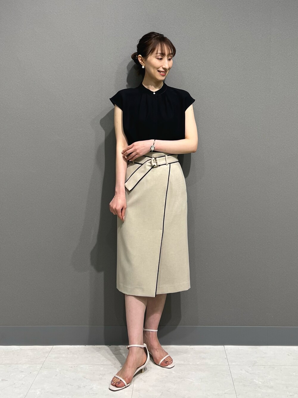 ブラック系のシャツ/ブラウス、ベージュ系のスカート、ホワイト系のサンダルを着用したレディースの春コーディネートの4枚目の写真