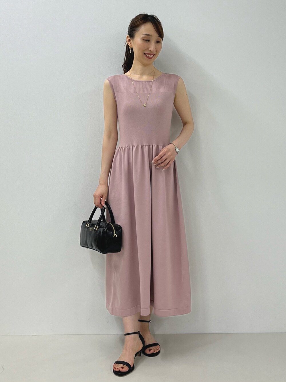 ピンク系のワンピース、ブラック系のサンダル、ゴールド系のピアス(両耳用)を着用したレディースの夏コーディネートの3枚目の写真