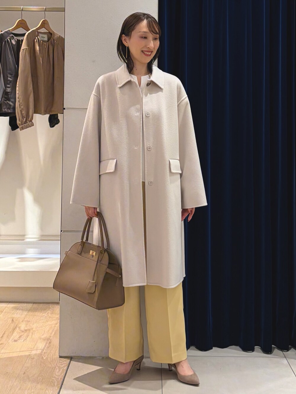 ベージュ系のステンカラーコート、ホワイト系のTシャツ/カットソー、イエロー系のその他パンツを着用したレディースの秋コーディネートの4枚目の写真