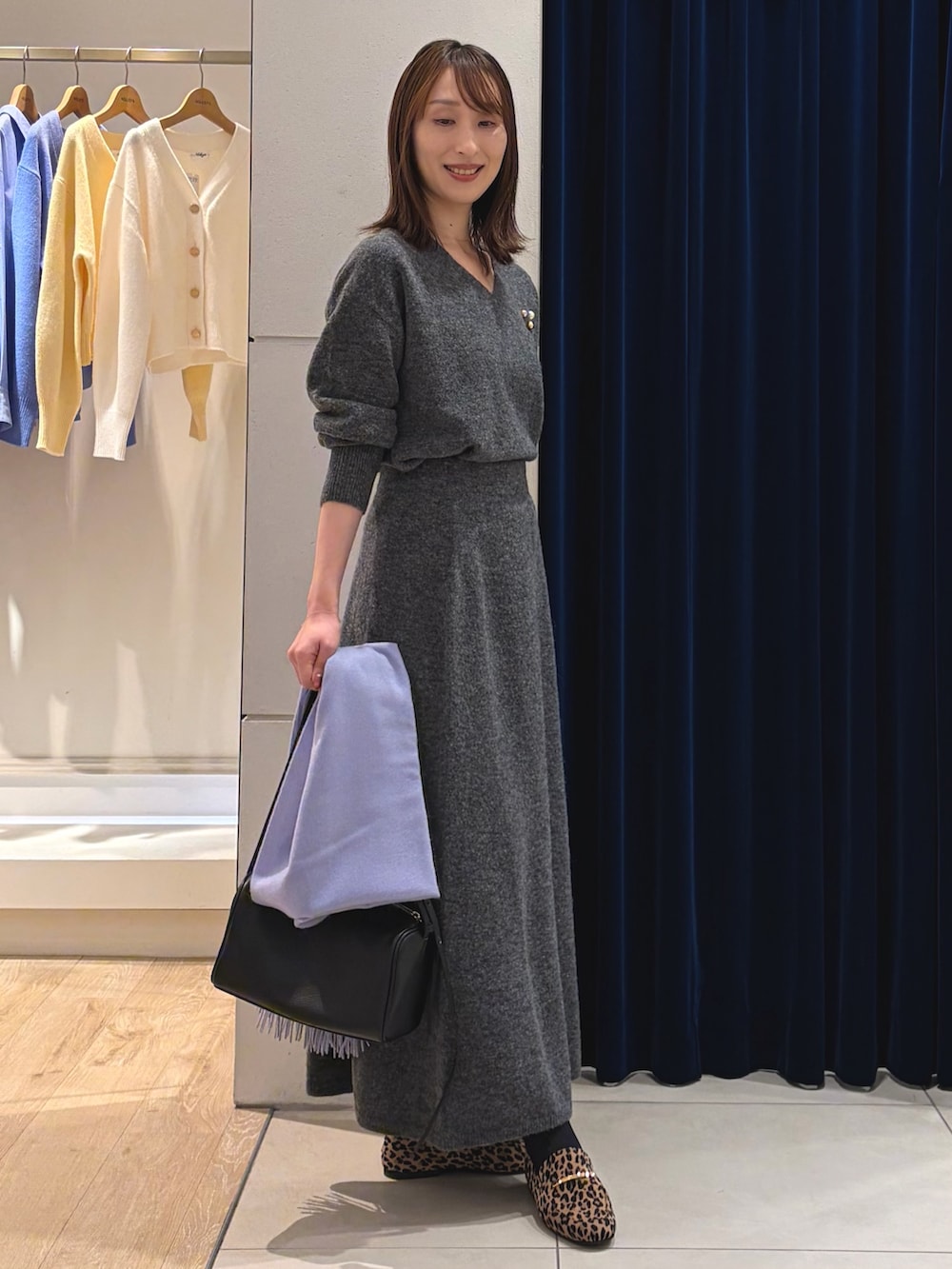 グレー系のニット/セーター、グレー系のスカート、ブラック系のショルダーバッグを着用したレディースの冬コーディネートの10枚目の写真