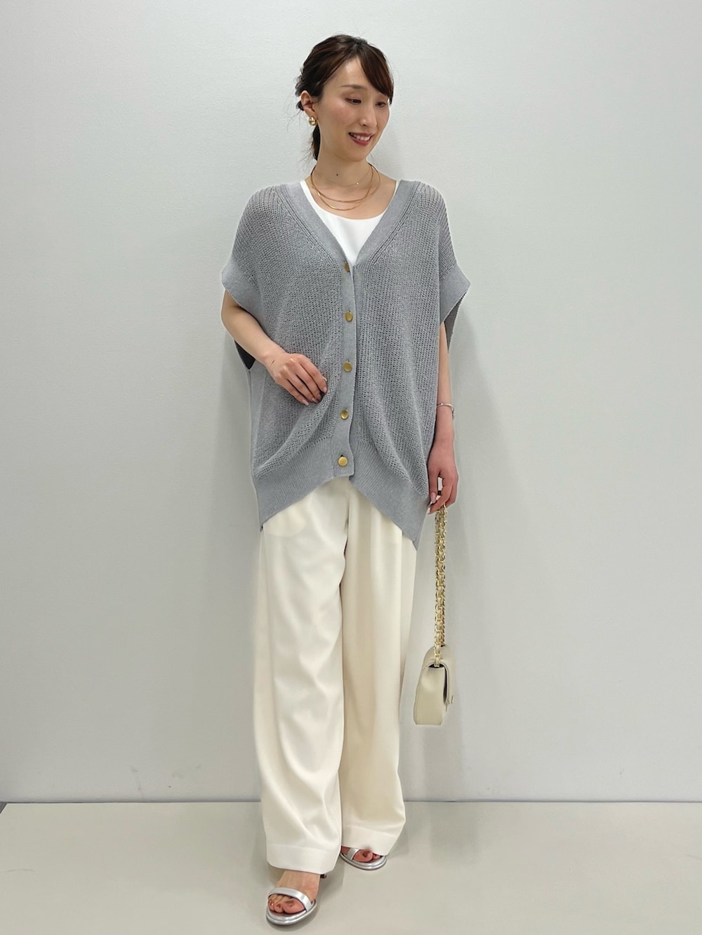 グレー系のベスト、ホワイト系のタンクトップ、ホワイト系のその他パンツを着用したレディースの春コーディネートの3枚目の写真