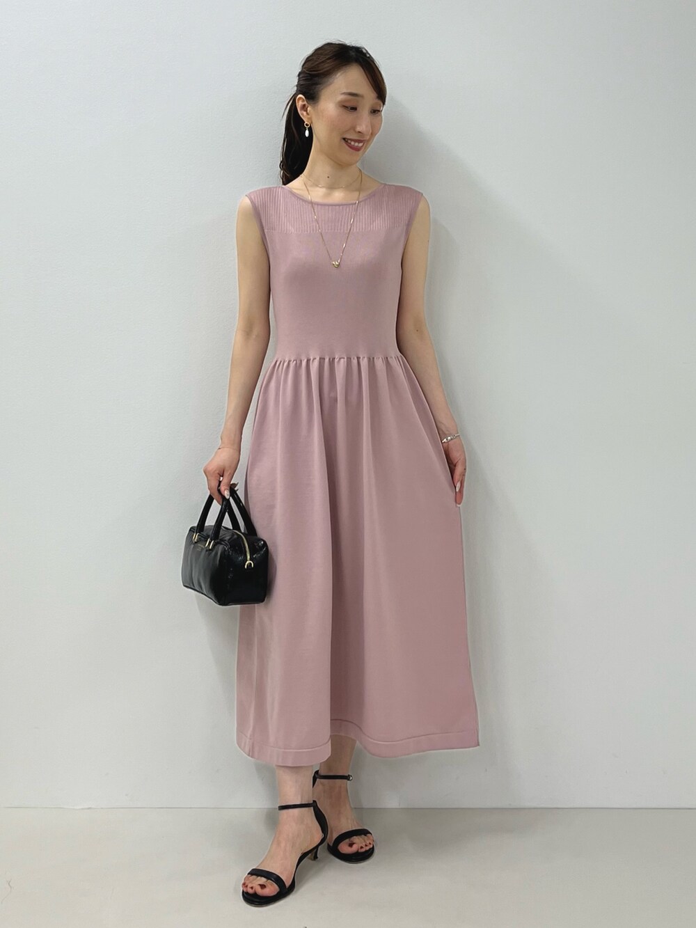 ピンク系のワンピース、ブラック系のサンダル、ゴールド系のピアス(両耳用)を着用したレディースの夏コーディネートの2枚目の写真