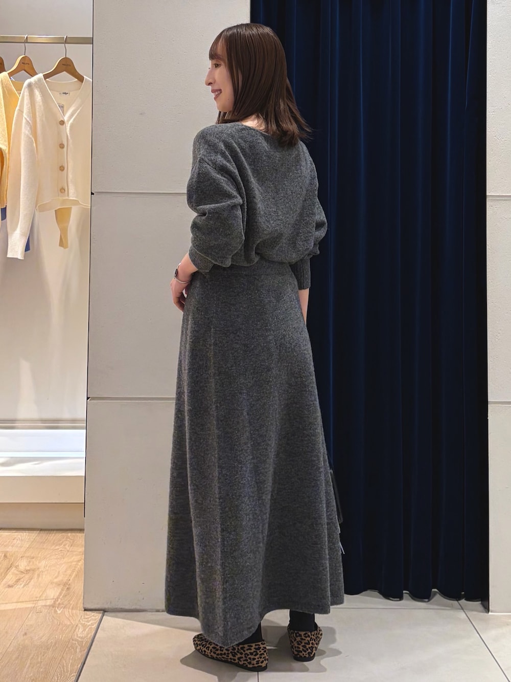 グレー系のニット/セーター、グレー系のスカート、ブラック系のショルダーバッグを着用したレディースの冬コーディネートの9枚目の写真