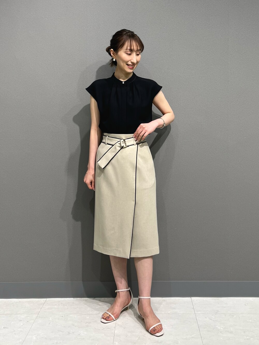 ブラック系のシャツ/ブラウス、ベージュ系のスカート、ホワイト系のサンダルを着用したレディースの春コーディネートの3枚目の写真