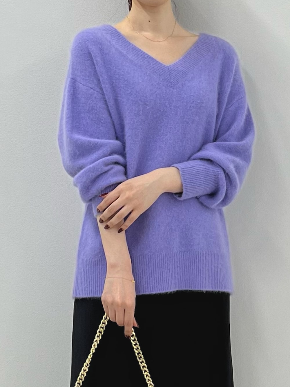 パープル系のニット/セーター、ゴールド系のショルダーバッグ、ブラック系のスカートを着用したレディースの秋コーディネートの3枚目の写真