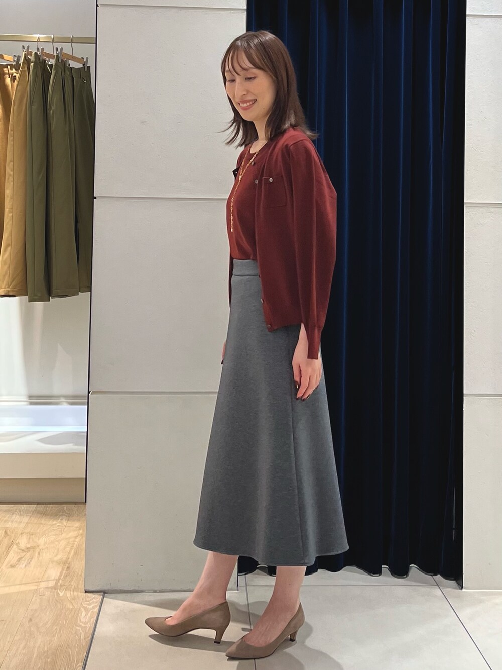 レッド系のニット/セーター、レッド系のカーディガン/ボレロ、グレー系のスカートを着用したレディースの秋コーディネートの8枚目の写真