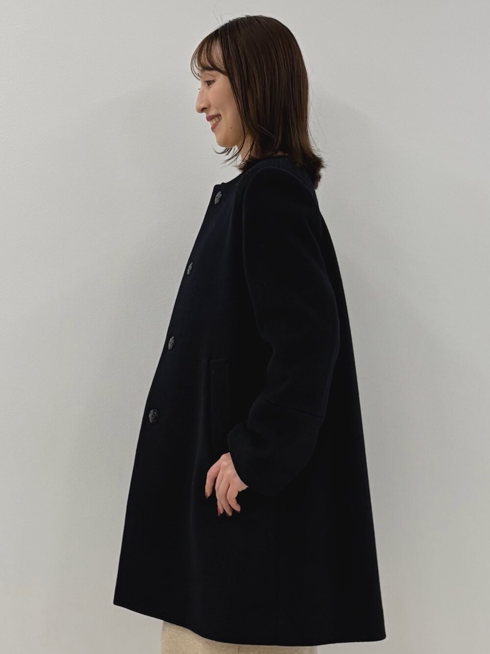 ブルー系のノーカラーコート、ベージュ系のワンピース、ベージュ系のショルダーバッグを着用したレディースの秋コーディネートの5枚目の写真