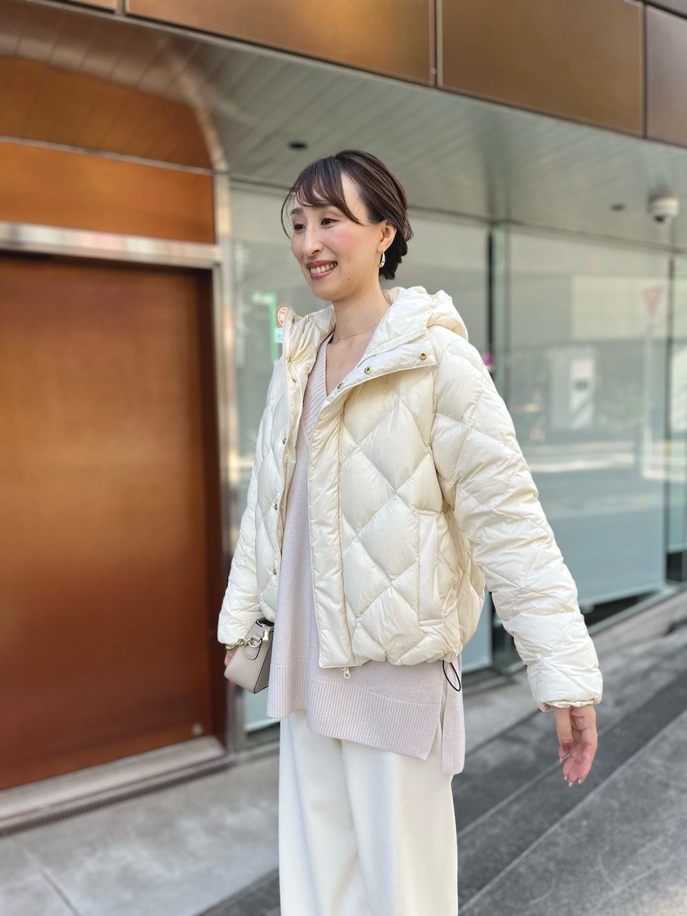 ホワイト系のダウンジャケット/コート、ベージュ系のニット/セーター、ベージュ系のショルダーバッグを着用したレディースの秋コーディネートの8枚目の写真