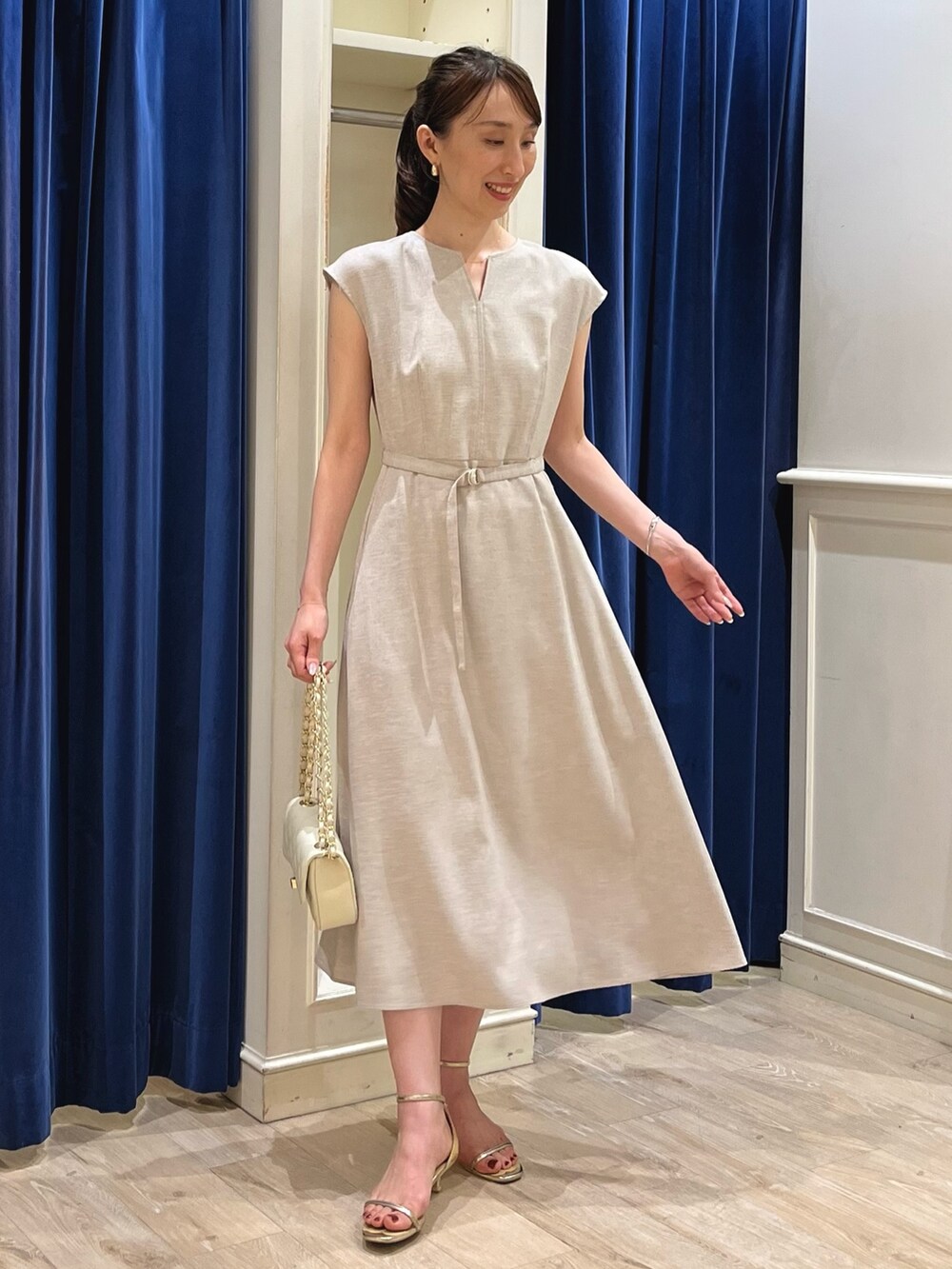 ベージュ系のワンピース、ホワイト系のショルダーバッグ、ゴールド系のサンダルを着用したレディースの夏コーディネートの2枚目の写真