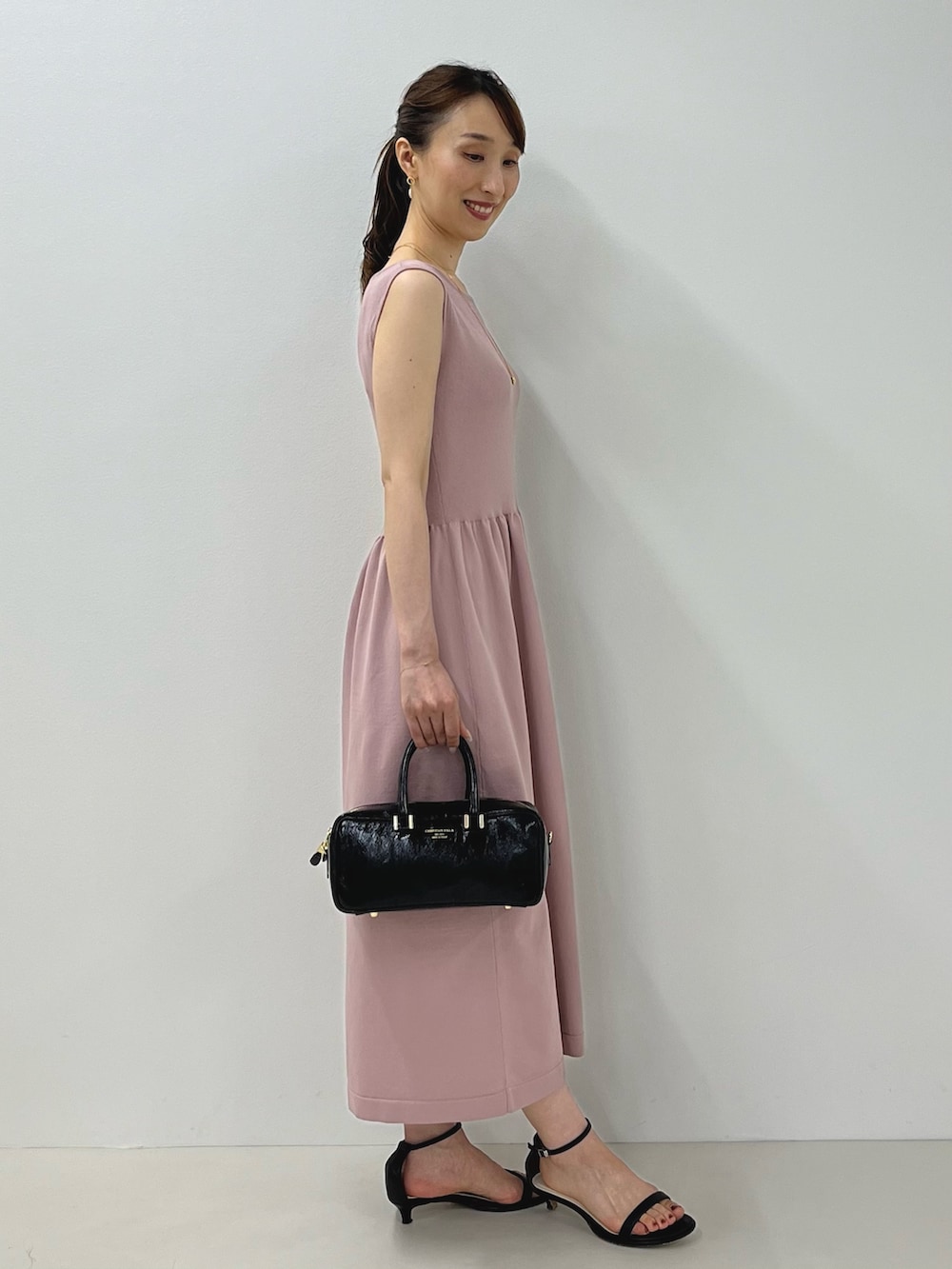 ピンク系のワンピース、ブラック系のサンダル、ゴールド系のピアス(両耳用)を着用したレディースの夏コーディネートの9枚目の写真