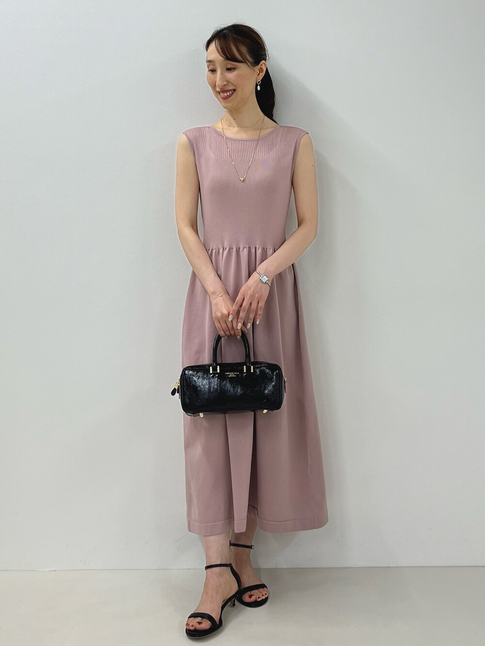 ピンク系のワンピース、ブラック系のサンダル、ゴールド系のピアス(両耳用)を着用したレディースの夏コーディネートの4枚目の写真