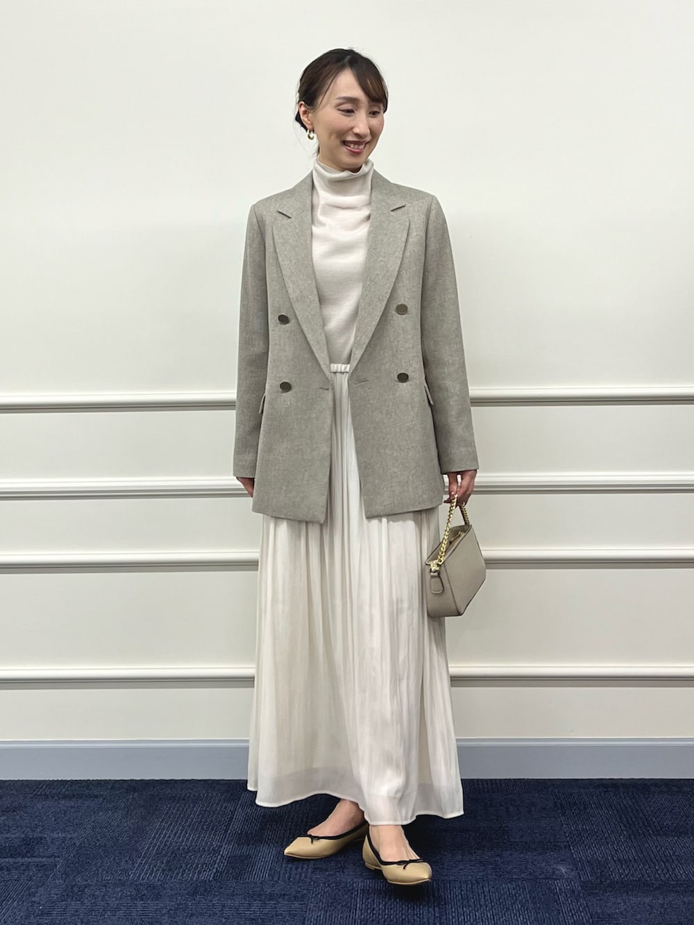 ゴールド系のニット/セーター、ベージュ系のテーラードジャケット、ホワイト系のスカートを着用したレディースの秋コーディネートの2枚目の写真