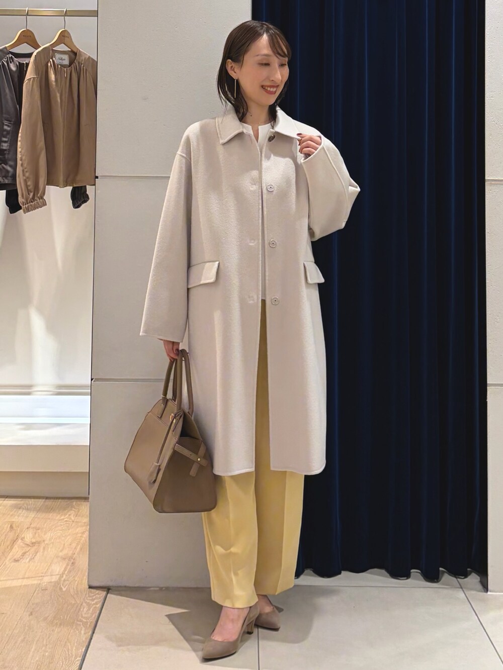 ベージュ系のステンカラーコート、ホワイト系のTシャツ/カットソー、イエロー系のその他パンツを着用したレディースの秋コーディネートの3枚目の写真