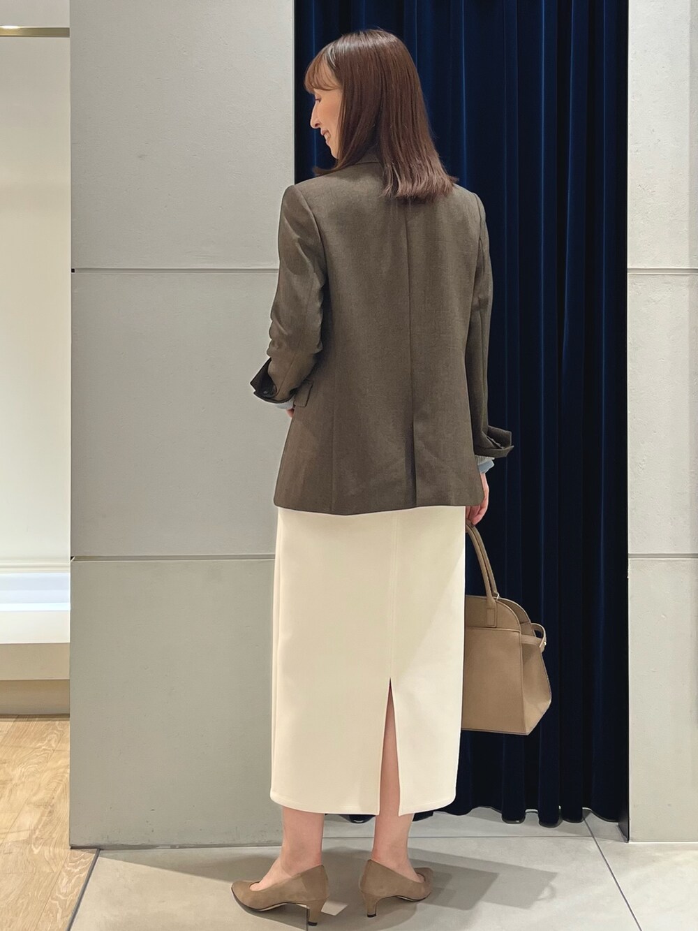 ブラウン系のテーラードジャケット、ブルー系のニット/セーター、ホワイト系のスカートを着用したレディースの秋コーディネートの10枚目の写真