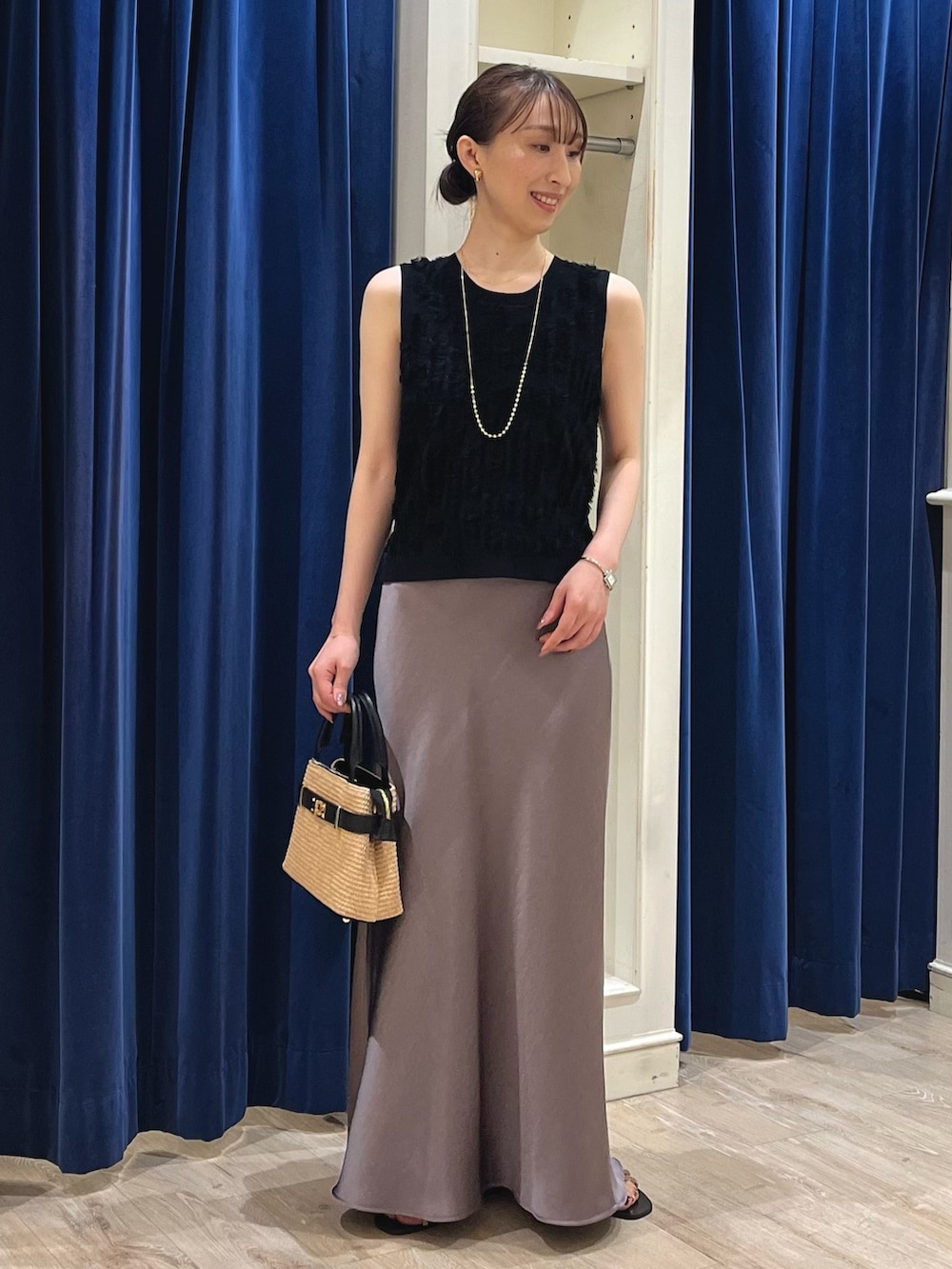 ブラック系のニット/セーター、グリーン系のスカート、ブラック系のかごバッグを着用したレディースの春コーディネートの7枚目の写真