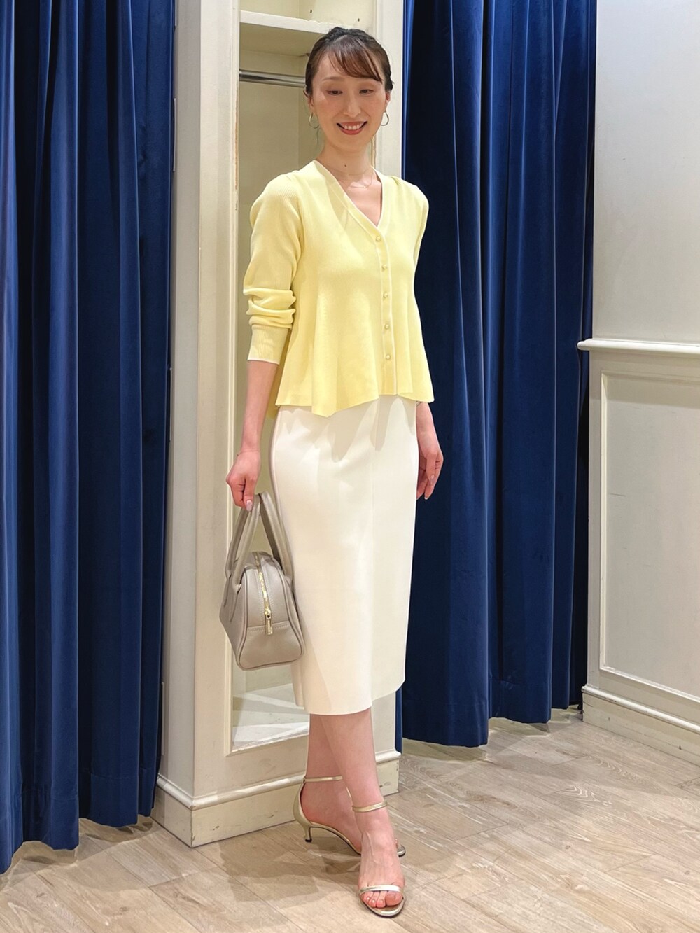 ベージュ系のカーディガン/ボレロ、ホワイト系のスカート、ベージュ系のボストンバッグを着用したレディースの春コーディネートの7枚目の写真