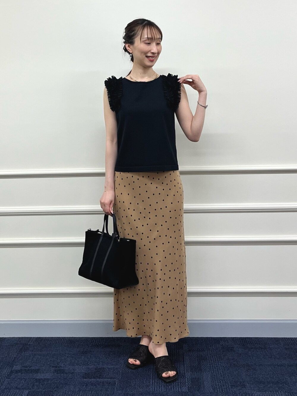 ブラック系のニット/セーター、ブラウン系のスカート、ブラック系のトートバッグを着用したレディースの夏コーディネートの6枚目の写真