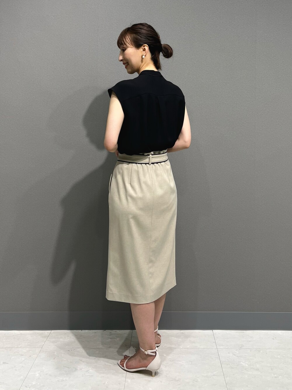 ブラック系のシャツ/ブラウス、ベージュ系のスカート、ホワイト系のサンダルを着用したレディースの春コーディネートの5枚目の写真