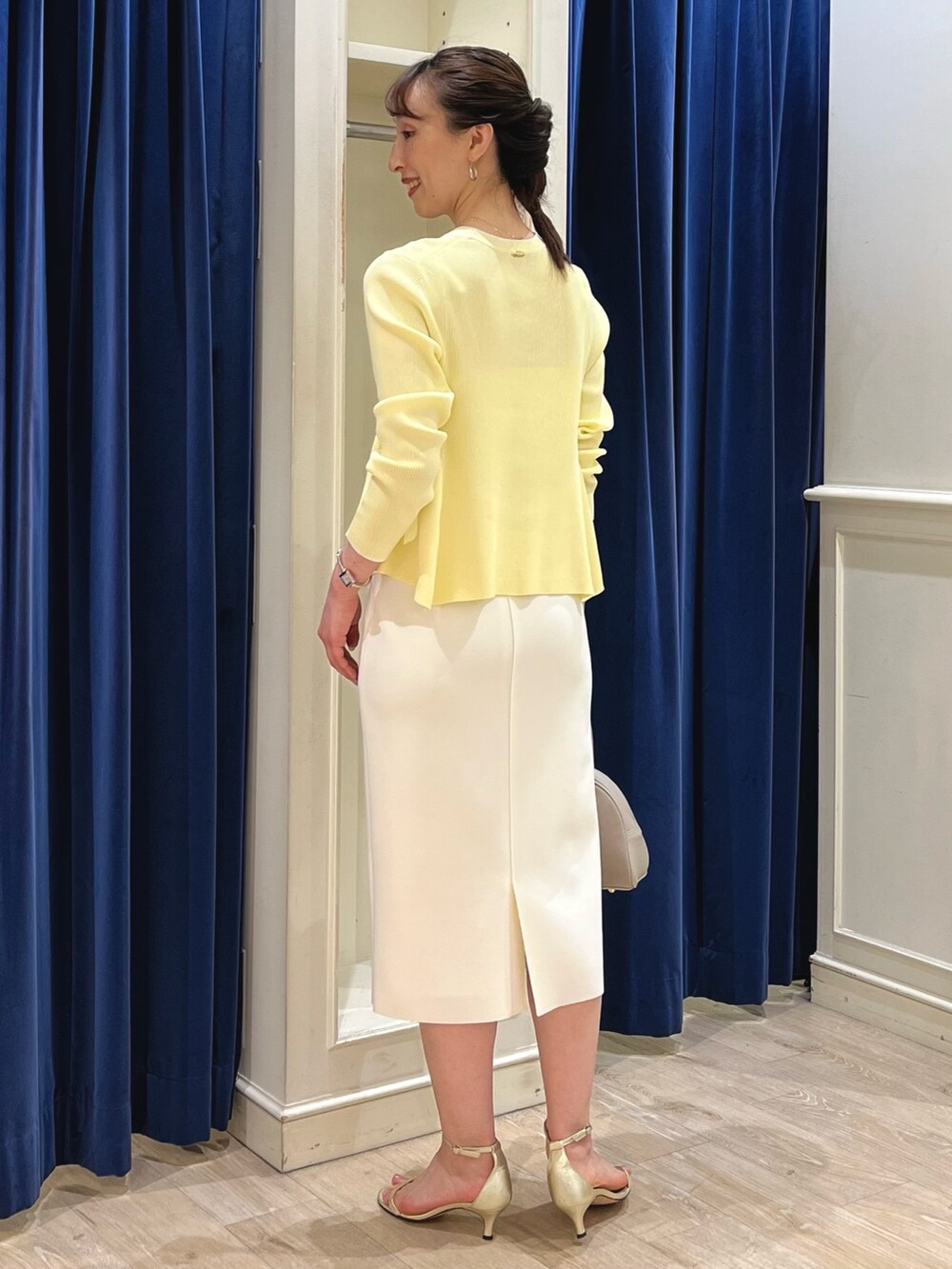 ベージュ系のカーディガン/ボレロ、ホワイト系のスカート、ベージュ系のボストンバッグを着用したレディースの春コーディネートの10枚目の写真