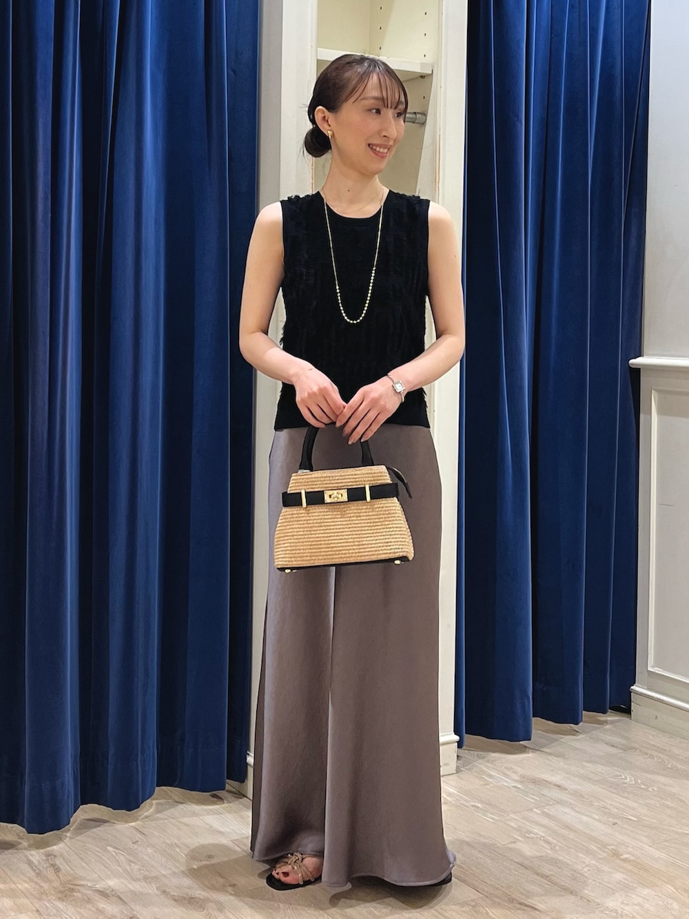 ブラック系のニット/セーター、グリーン系のスカート、ブラック系のかごバッグを着用したレディースの春コーディネートの2枚目の写真