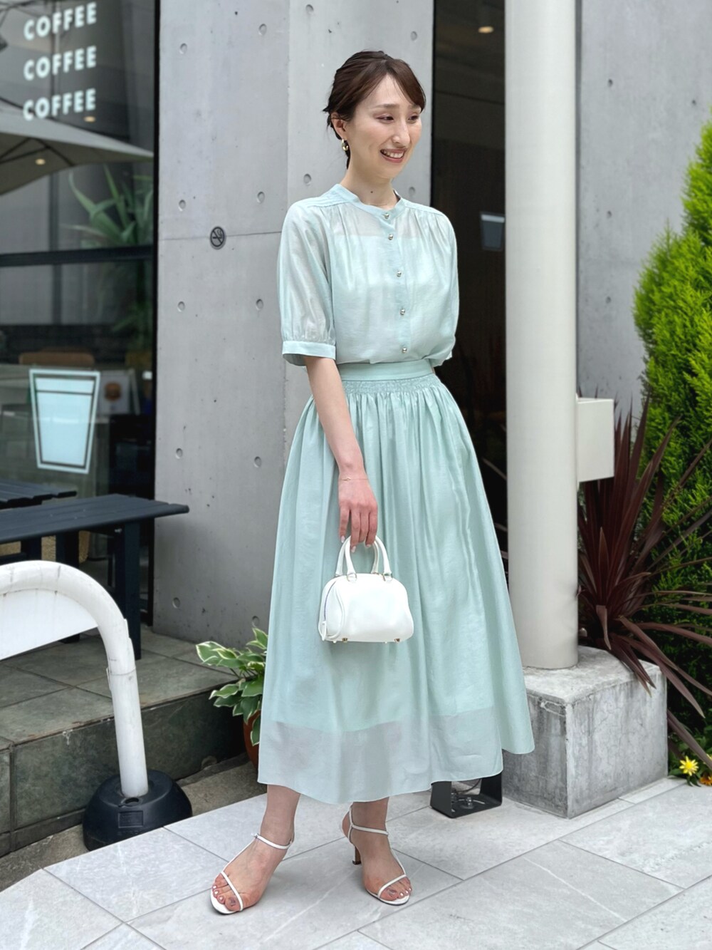 グリーン系のシャツ/ブラウス、グリーン系のスカート、ホワイト系のボストンバッグを着用したレディースの春コーディネートの3枚目の写真