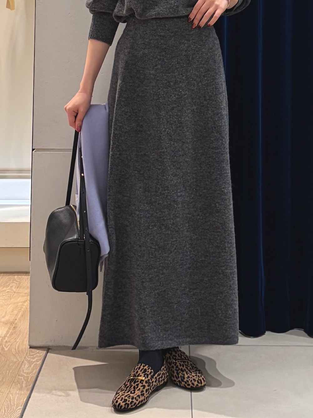 グレー系のニット/セーター、グレー系のスカート、ブラック系のショルダーバッグを着用したレディースの冬コーディネートの4枚目の写真