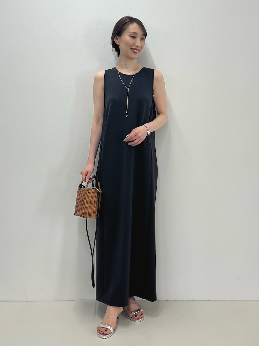 グレー系のワンピース、イエロー系のかごバッグ、シルバー系のサンダルを着用したレディースの春コーディネートの2枚目の写真