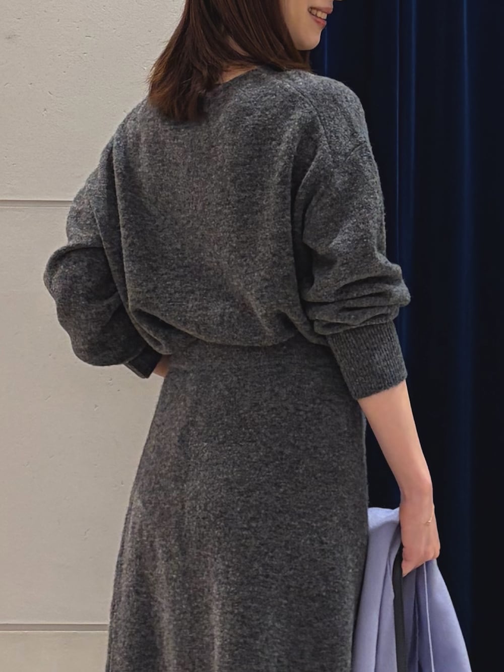 グレー系のニット/セーター、グレー系のスカート、ブラック系のショルダーバッグを着用したレディースの冬コーディネートの5枚目の写真