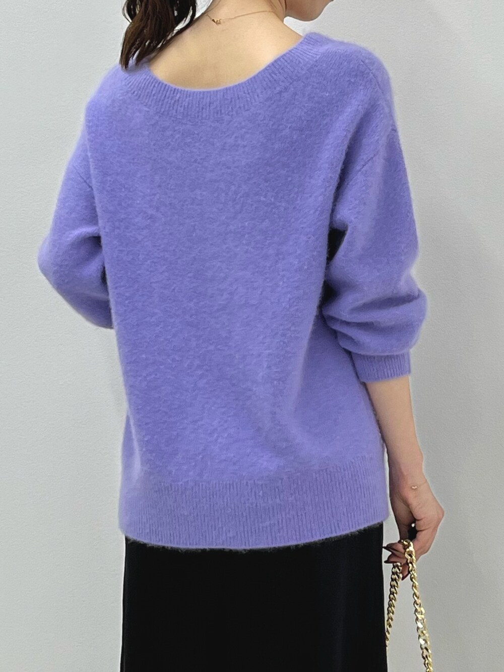 パープル系のニット/セーター、ゴールド系のショルダーバッグ、ブラック系のスカートを着用したレディースの秋コーディネートの7枚目の写真