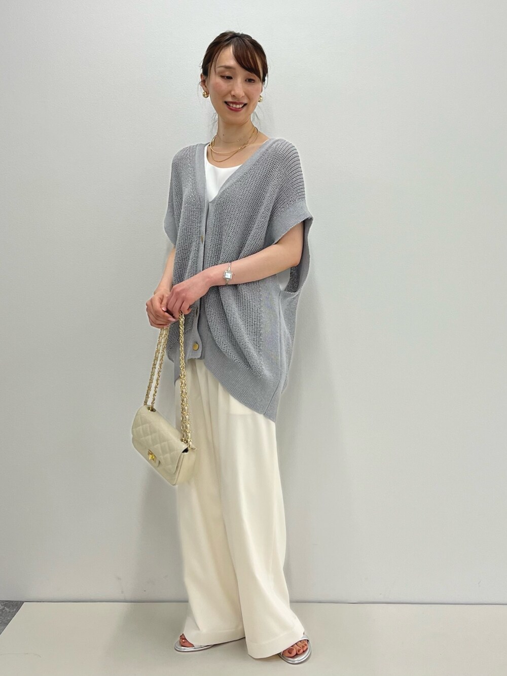 グレー系のベスト、ホワイト系のタンクトップ、ホワイト系のその他パンツを着用したレディースの春コーディネートの6枚目の写真