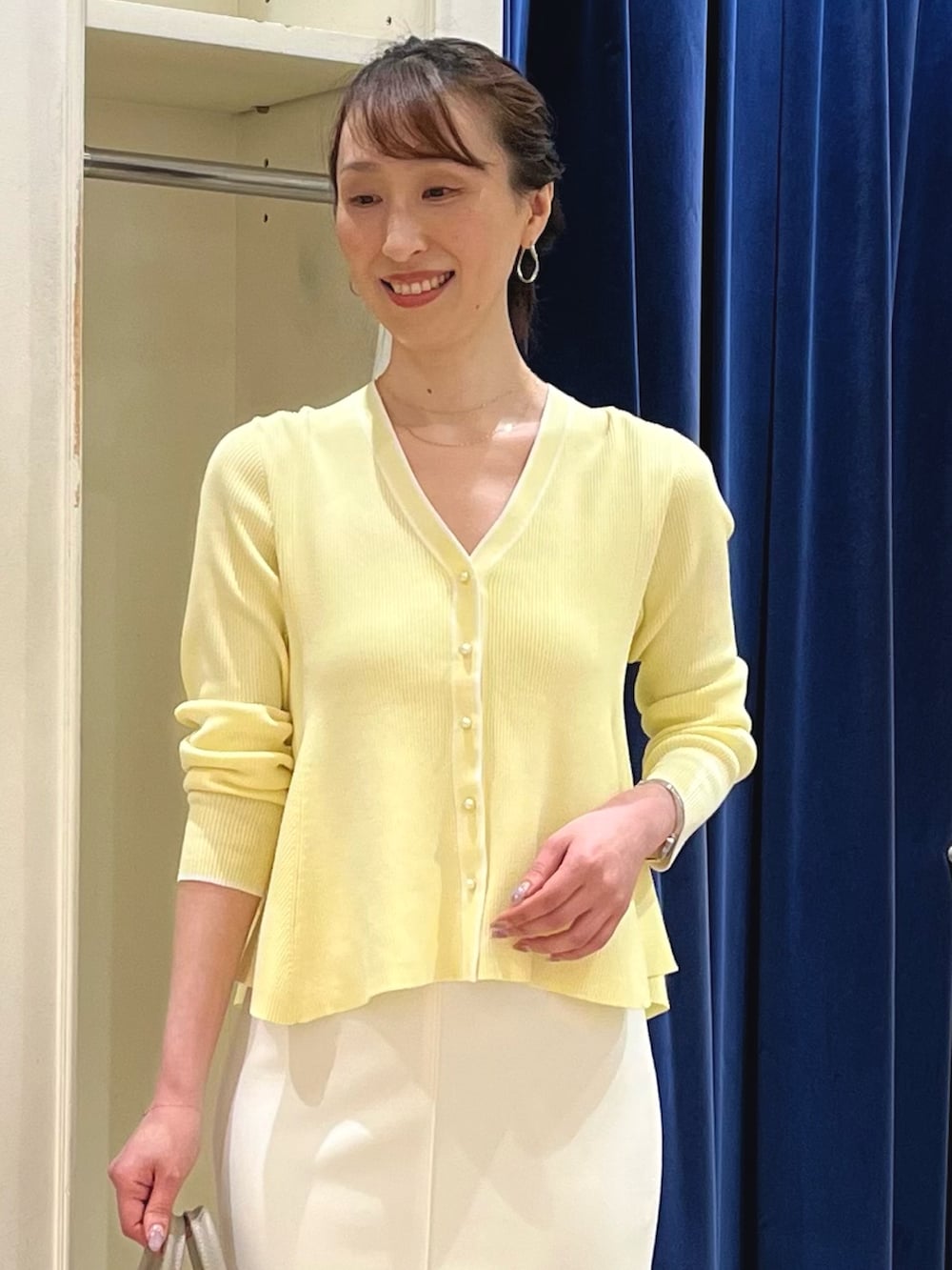 ベージュ系のカーディガン/ボレロ、ホワイト系のスカート、ベージュ系のボストンバッグを着用したレディースの春コーディネートの3枚目の写真