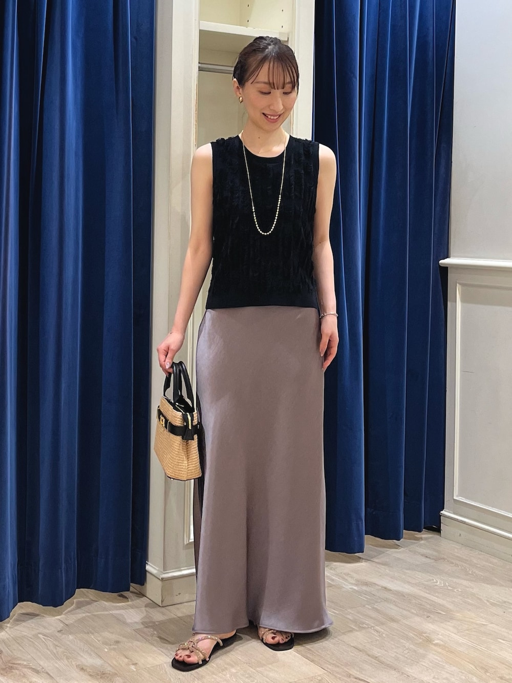 ブラック系のニット/セーター、グリーン系のスカート、ブラック系のかごバッグを着用したレディースの春コーディネートの6枚目の写真